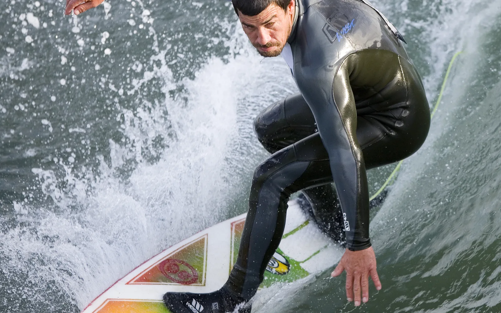 A surfer riding a wave near a pier in California